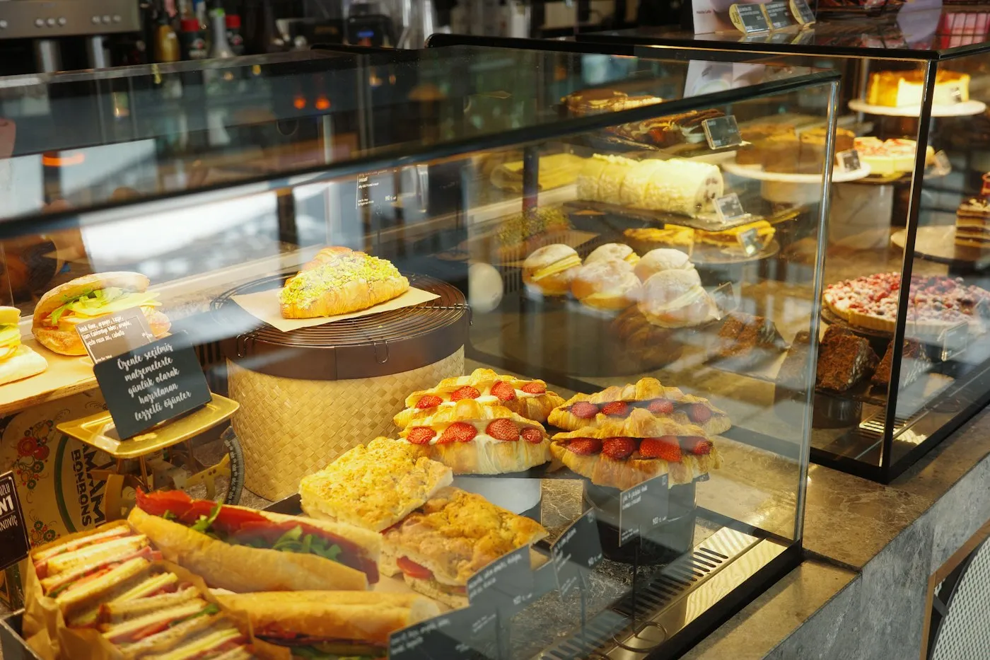 A café display case with sandwiches, croissants and cakes